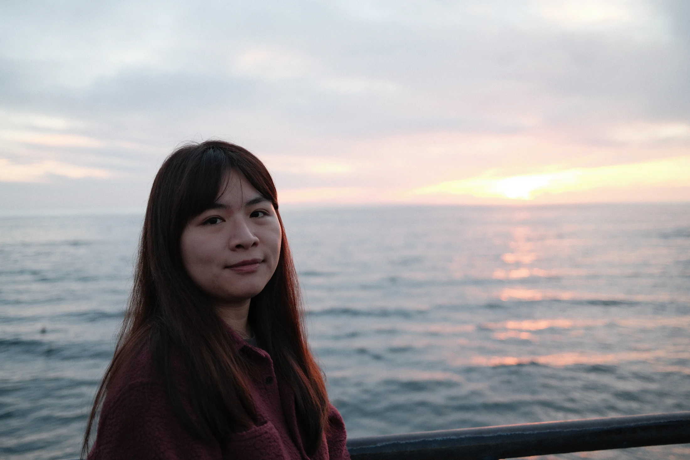 黃翊雅站在海邊,身後是日落與海面